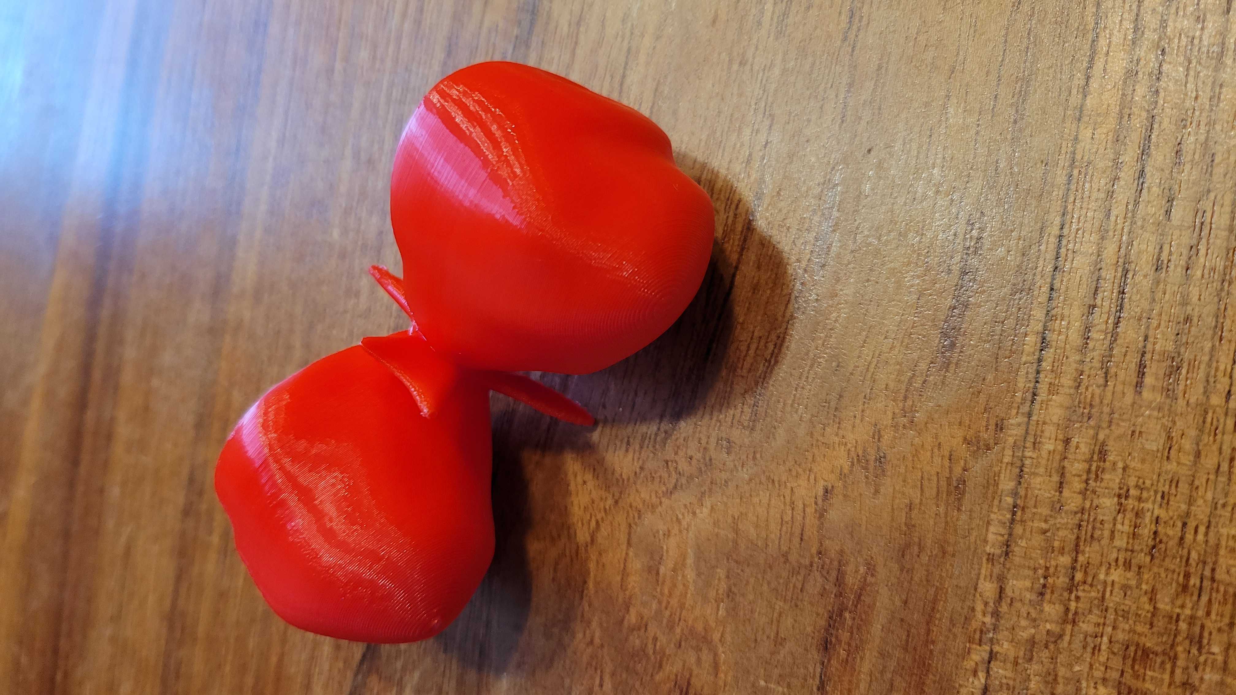 Photo of a 3D print of Eta Carinae, a mature star system. The print is about 5 inches in length and built from red plastic. The mode looks like a butterfly whose wings have been replaced by 2 small balloons that meet from end to end.